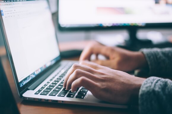 A photo of a laptop with two hands typing on the keyboard. | © Davos Klosters Mountains