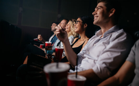 A group of friends watches a film and enjoy their visit in the cinema together. | © Shutterstock