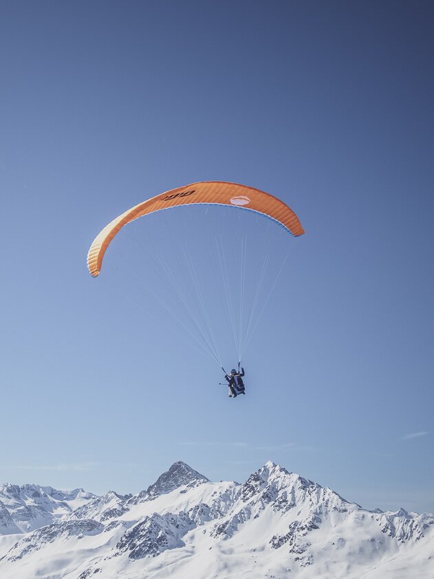 Paragliding flight winter panorama | © Davos Klosters Mountains A paraglider pilot enjoys the flight in front of a snowy mountain panorama. | © Davos Klosters Mountains