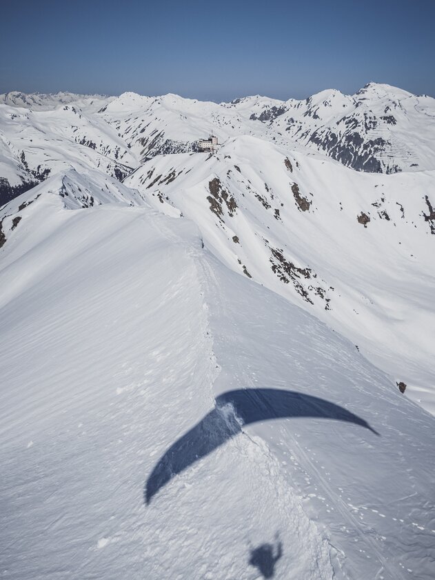 Shadow paraglider ridge | © Davos Klosters Mountains The shadow of the paraglider falls on the snowy ridge that leads to the Jatzhorn and Jakobshorn. | © Davos Klosters Mountains