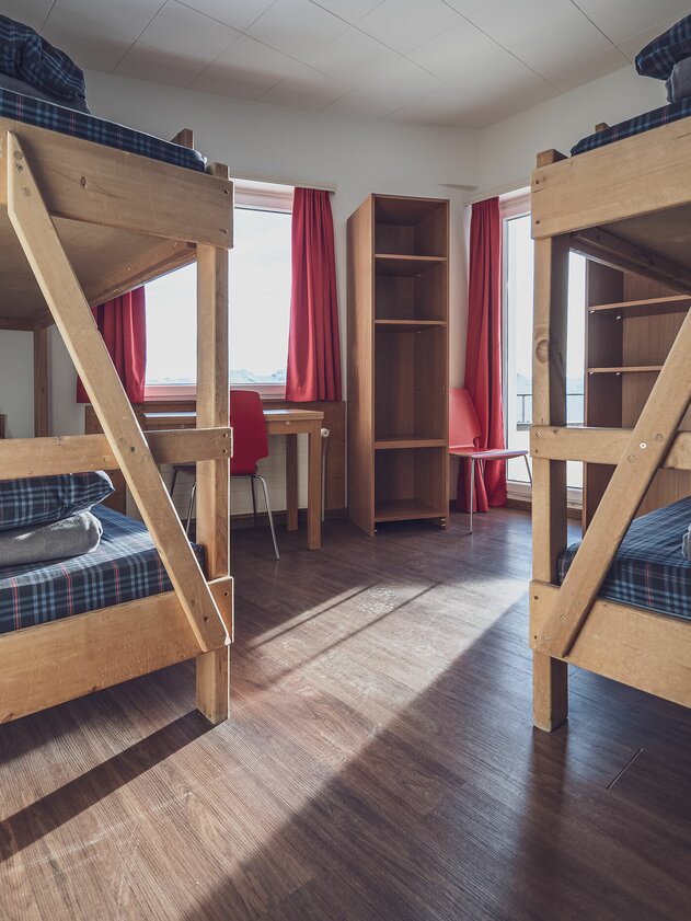 Mehrbettzimmer mit Stockbetten, Tisch, Stuhl und Kleiderablagen | © Davos Klosters Mountains Multi-bed room with bunk beds, table, chair and clothes storage | © Davos Klosters Mountains