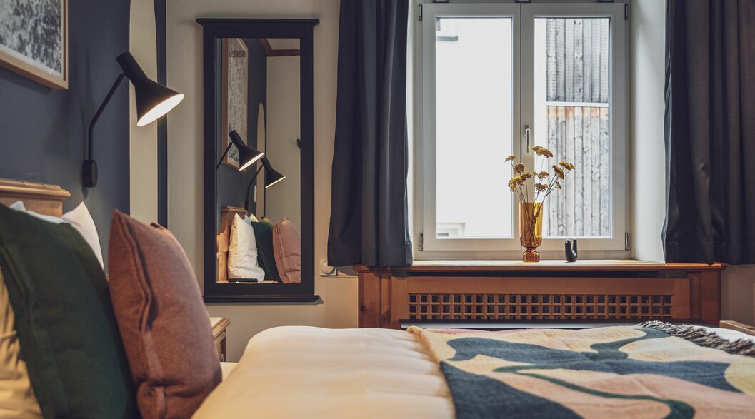 Doppelbettzimmer mit Bettwäsche, Fenster, Spiegel und Nachttischlampe | © Davos Klosters Mountains 