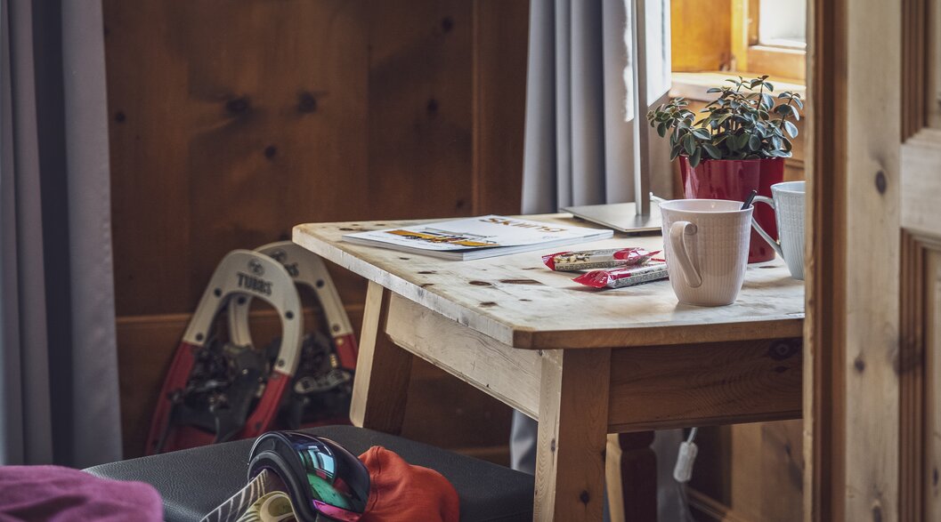 Schreibtisch im Hotelzimmer mit Schneeschuhen und Skibrille | © Davos Klosters Mountains