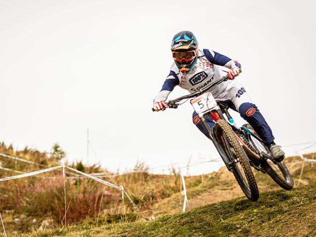 In voller Montur fährt der Downhill  Biker an einem Rennen mit.  | © Matteo Manno