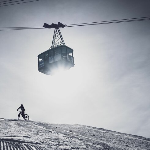 Fatbike Abfahrt auf Pischa mit der Gondel, die über den Weg schwebt. | © Davos Klosters Mountains