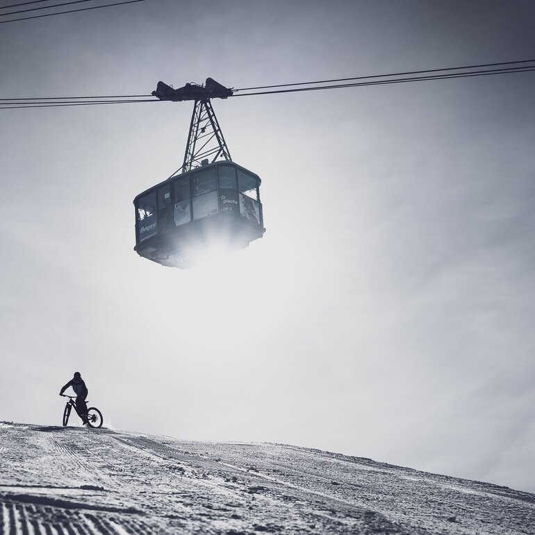 Fatbike Abfahrt auf Pischa mit der Gondel, die über den Weg schwebt. | © Davos Klosters Mountains