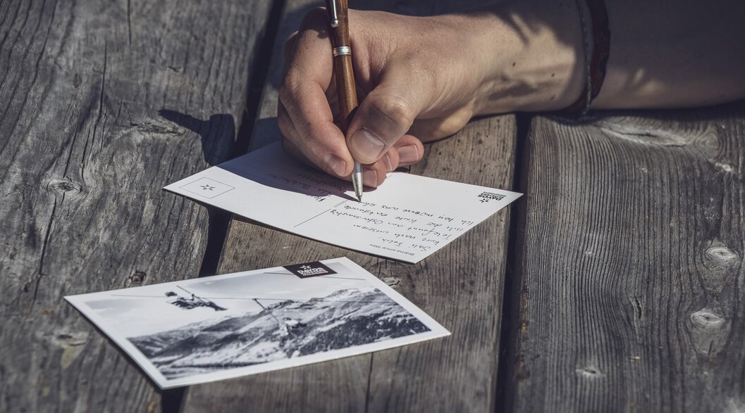 Postkarte aus den Bergen | © Davos Klosters Mountains Nahaufnahme einer Hand welche soeben eine Postkarte schreibt. | © Davos Klosters Mountains