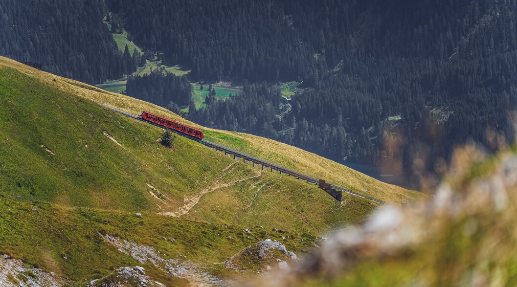 Die rote Parsennbahn fährt den Berg hoch, dahinter liegt das Tal von Davos. | © Davos Klosters Mountains