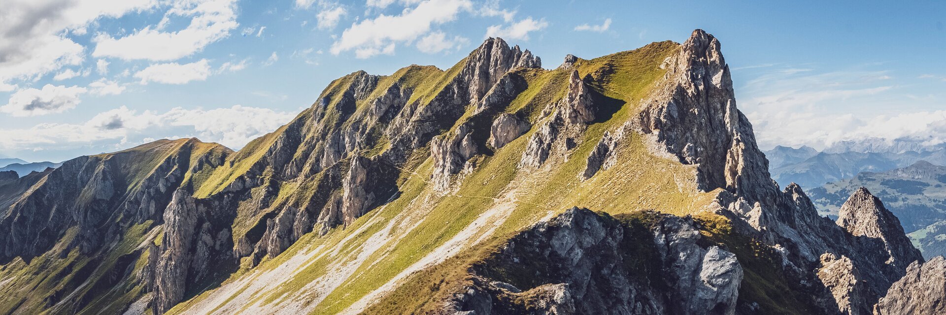 Ein Pfad schlängelt sich über den grünen Hang der Casanna, ein traumhafter Blick vom Gipfel des Grüenhorns.  | © Davos Klosters Mountains