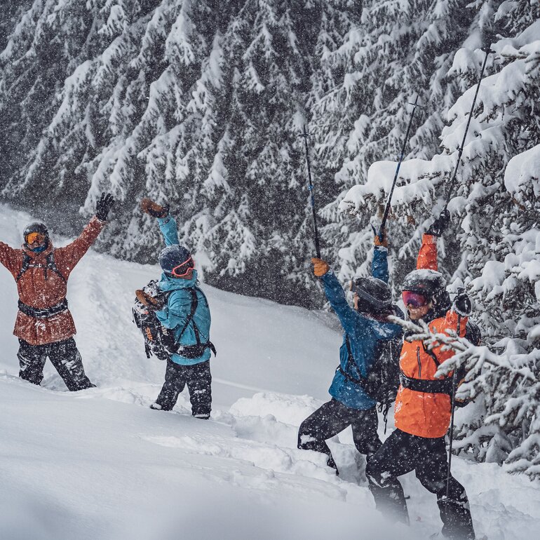 A group of freeriders stand in the deep snow on the Rinerhorn and celebrate the fact that it is snowing.  | © Davos Klosters Mountains