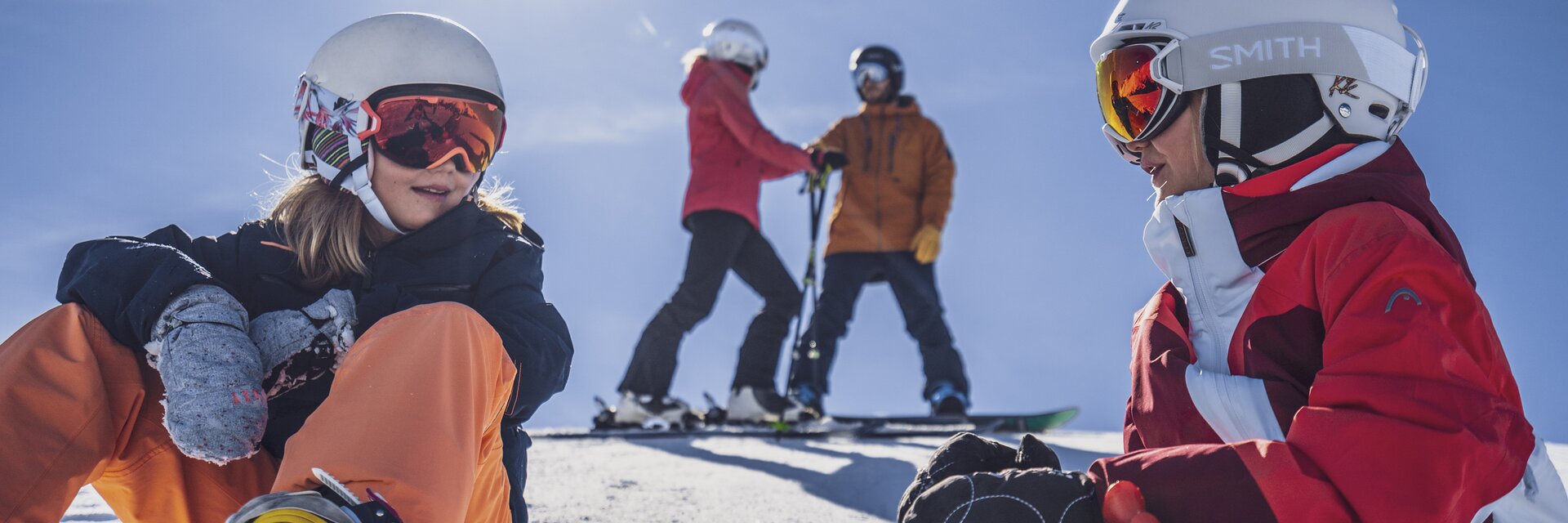 Familientag am Rinerhorn | © Davos Klosters Mountains Zwei Mädchen mit ihren Eltern im Hintergrund machen eine Pause auf der Piste. | © Davos Klosters Mountains