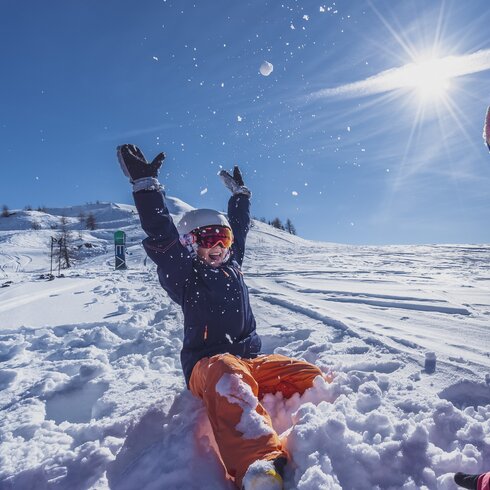 Mutter und Tochter spielen im Tiefschnee bei Sonnenschein. | © Davos Klosters Mountains