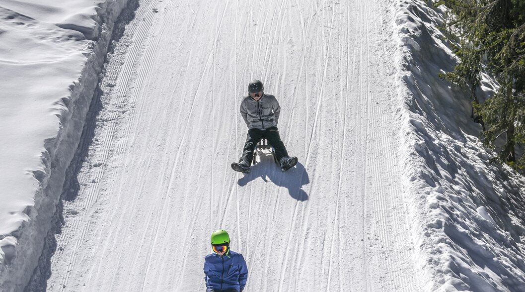 Gruppe junge Schlittler sausen die präparierte Schlittelpiste hinunter. | © Davos Klosters Mountains