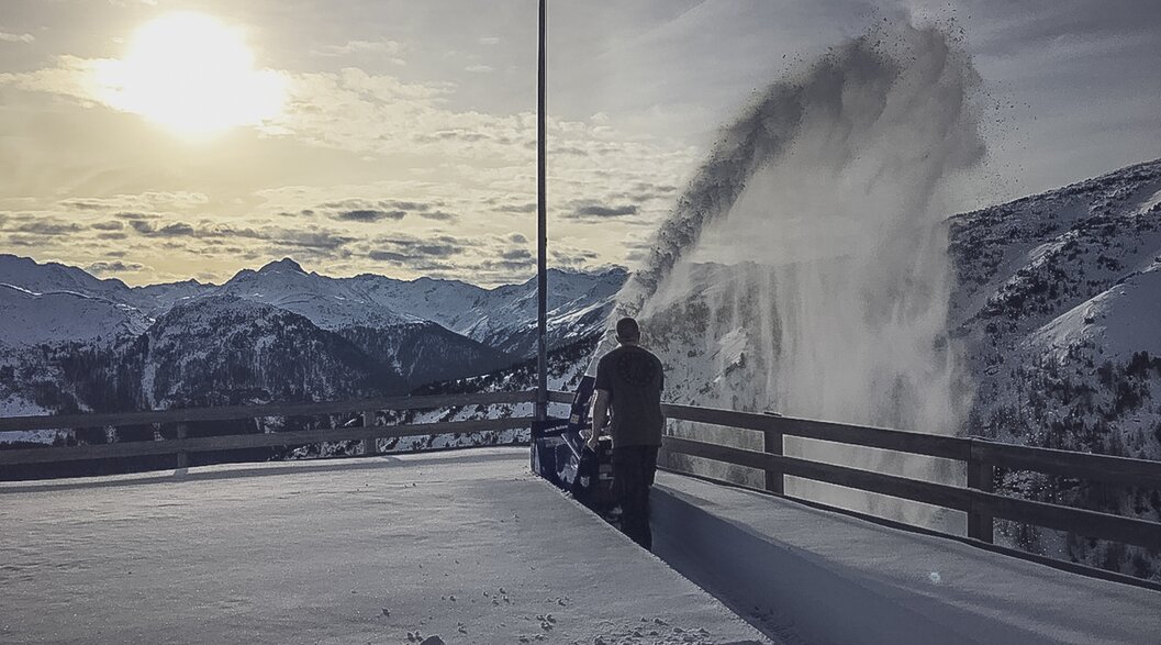 Ein Mann schleudert Neuschnee von der Terrasse der Gruobenalp mit einer Schneefräse. | © Davos Klosters Mountains