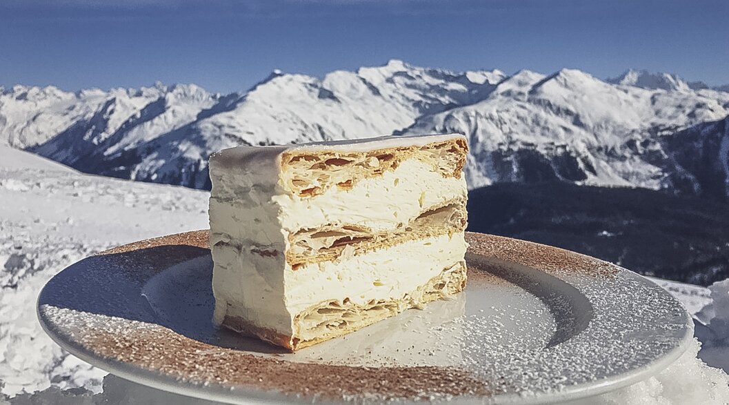 Die legendäre Cremeschnitte der Gruobenalp mit traumhaftem Bergpanorama im Hintergrund. | © Davos Klosters Mountains