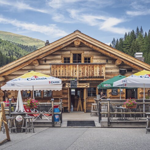 Exterior view of the rustic Blockhuus with its sun terrace in the summer. | © Davos Klosters Mountains