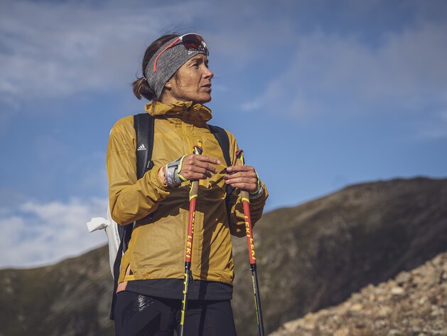 Trailrunning Trainerin Jasmin Nunige | © Davos Klosters Mountains Trainerin Jasmin Nunige blickt auf die rechte Seite in die Ferne, in den Händen hat Sie Laufstöcke. | © Davos Klosters Mountains