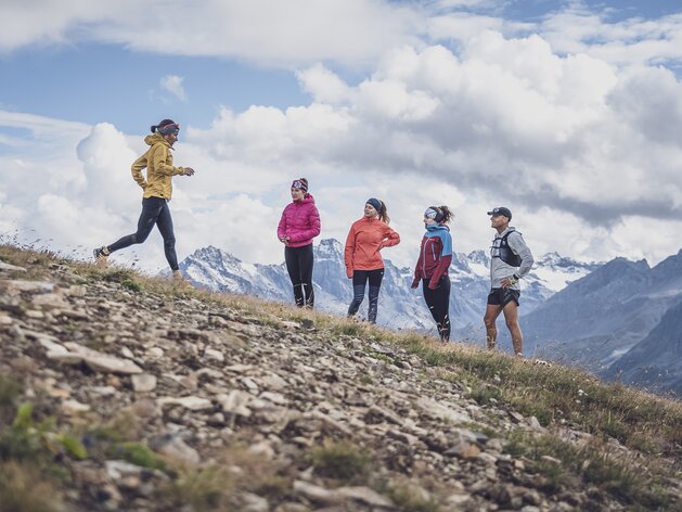 Trailrunning Lauftechnik bergab | © Davos Klosters Mountains Die Trainerin zeigt die dynamische Lauftechnik für das bergab laufen vor, vier Läufer schauen zu. | © Davos Klosters Mountains
