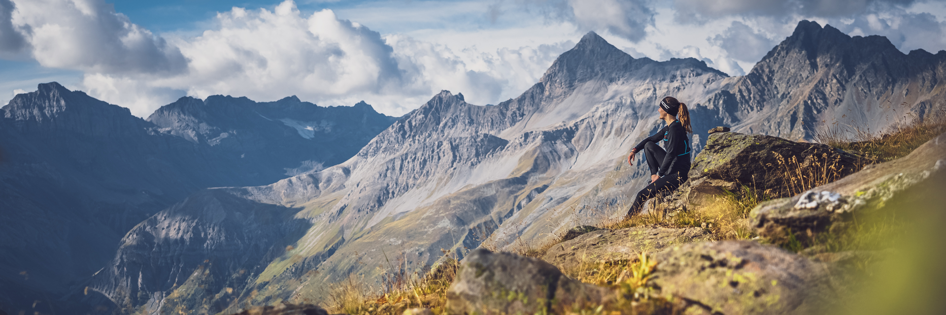 Trailrunningpause | © Davos Klosters Mountains Trailrunnerin geniesst ihre Pause auf einem Stein und schaut in die Bergen. | © Davos Klosters Mountains