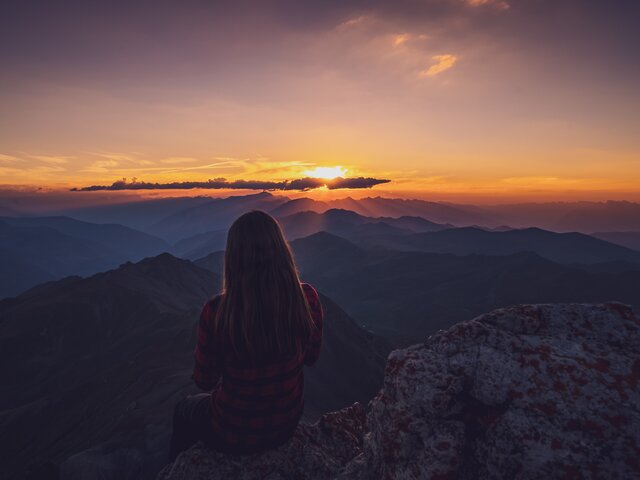 Sonnenuntergang in den Davos Klosters Mountains | © Davos Klosters Mountains Wandrerin geniesst den Sonnenuntergang auf dem Gipfel. | © Davos Klosters Mountains