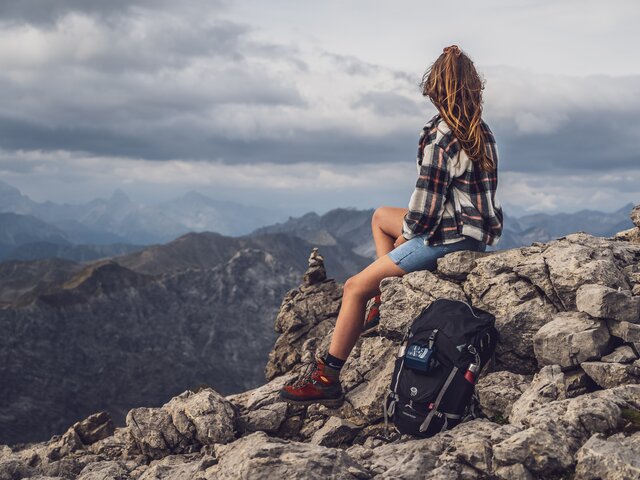 Wandern in den Davos Klosters Mountains | © Davos Klosters Mountains Eine Frau geniesst eine Pause vom Wandern auf einem Stein. | © Davos Klosters Mountains