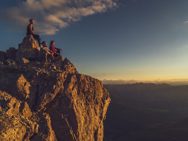 Drei Wanderer auf dem Gipfel | © Davos Klosters Mountains Drei Wanderer geniessen den Sonnenuntergang in den Davos Klosters Mountains. | © Davos Klosters Mountains
