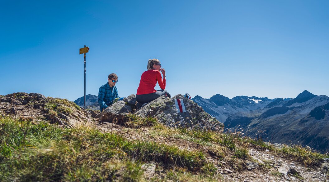 Zwei Leute picknicken auf dem Gipfel des Jatzhorns und geniessen den schönen Ausblick.  | © Davos Klosters Mountains