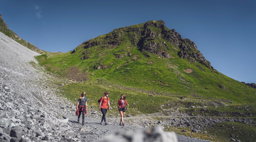 Drei Freunden haben Spass bei der Wanderung auf dem Felsenweg auf Parsenn.  | © Davos Klosters Mountains