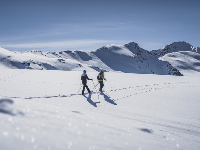 Two women walk through the deep snow on snowshoes. | © Davos Klosters Mountains