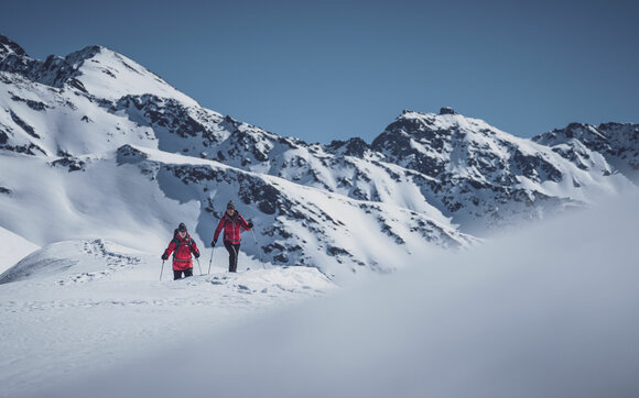 Ehepaar in rot gekleidet geniesst das Schneeschuhlaufen in Naherholungsgebiet Pischa. | © Davos Klosters Mountains