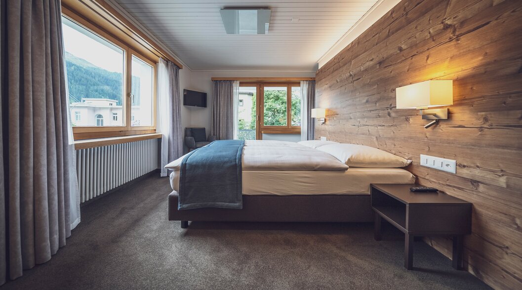 Hotelzimmer mit Doppelbett und grossen Fenstern mit Aussicht | © Davos Klosters Mountains