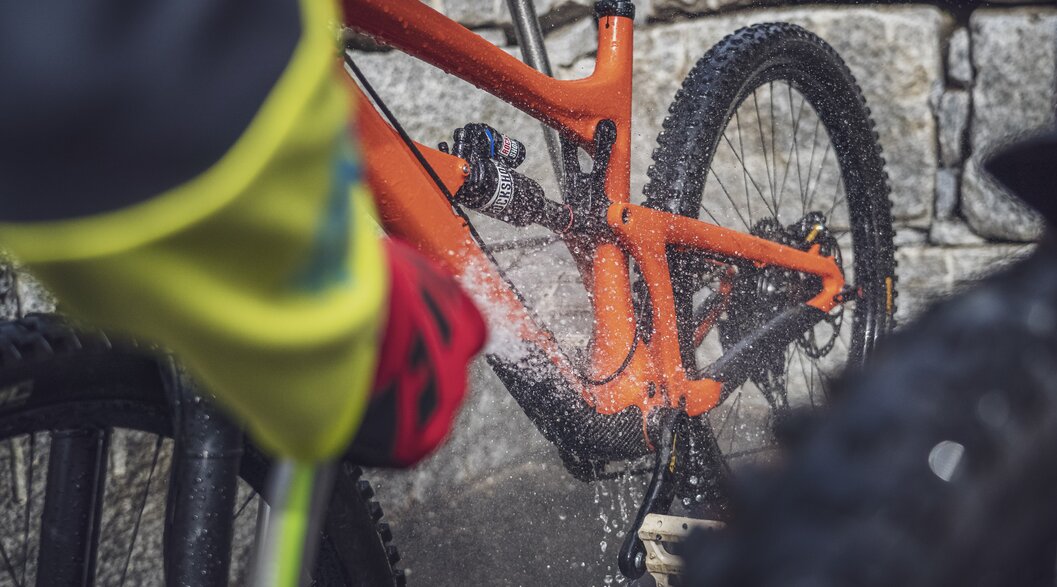 Das orange Mountainbike wird mit dem Wasserstrahl sauber gewaschen. | © Davos Klosters Mountains
